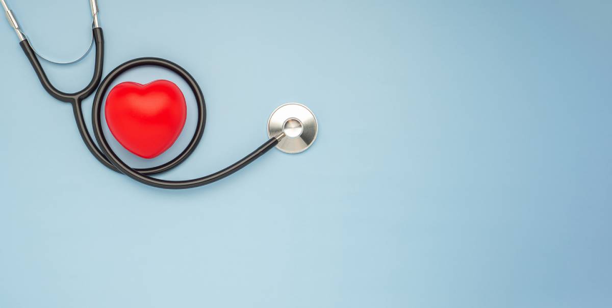 A stethoscope and red heart on a light blue background