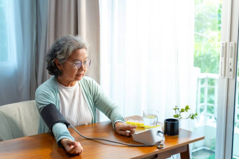 Asian elderly woman measuring blood pressure at home.