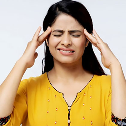 Stock image of an woman holding hands on forehead sides of eyes and feeling headache