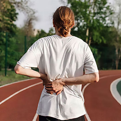 Stock image of an woman in running track holding her back and feeling pain